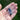Lavender Sprig Necklace held in hand with fingers visible in a flower field, highlighting the pendant design and natural outdoor lifestyle setting