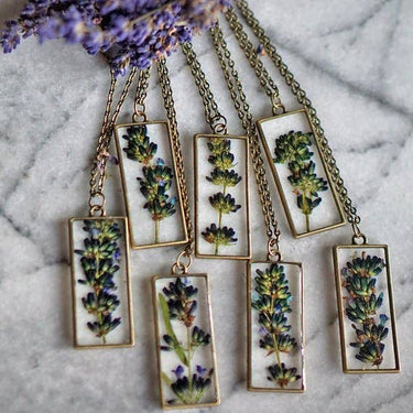 Lavender Pendant Necklace shown from a side angle in a lifestyle setting with multiple copies of the product, highlighting pendant profile, chain details, and product variety