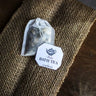 Bath Tea Relax product laid on a silk sheet over a wooden surface, showcasing packaging in a soft, neat setting