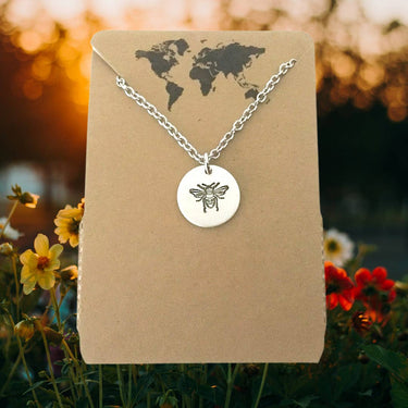 Bee necklace displayed on a lifestyle background