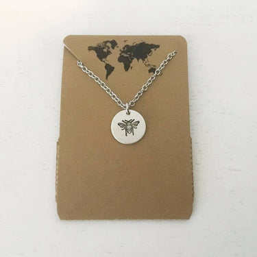 Bee necklace displayed on hang tag, showing design and 
packaging on a studio background