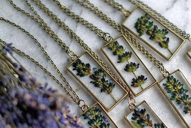 Lavender Pendant Necklace front view in a lifestyle setting with multiple copies of the product, showcasing pendant design, chains, and variety in a natural environment