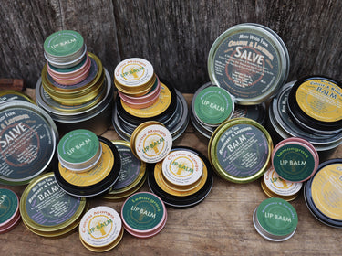 Rosemary & Lavender Lip Balm displayed with a variety of other lip balms and salves, showcasing multiple products, packaging designs, and product assortment